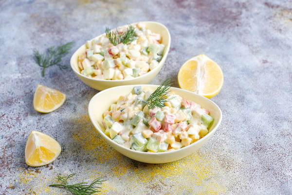 Maionese de Natal feita com batatas, legumes cozidos no vapor e maionese cremosa, servida em prato branco, decorada com ervas frescas e cores festivas. 