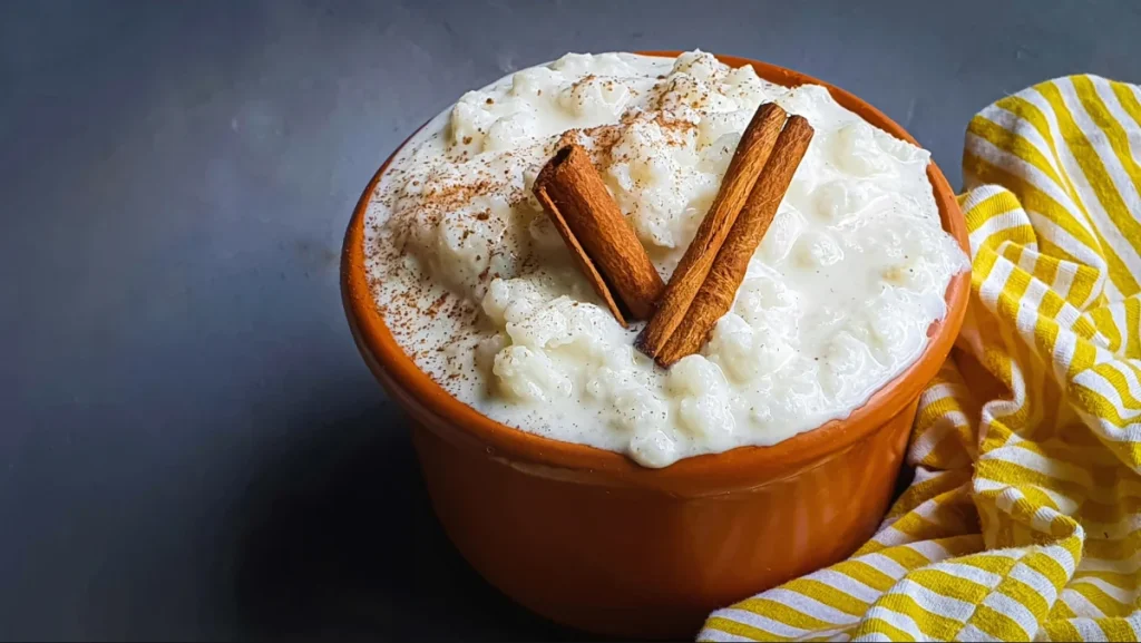 Canjica de milho doce com canela dentro de vasilha de louça marrom.