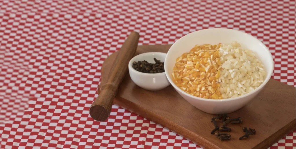 Vasilha de louça branca com canjica branca e canjica amarela sobre mesa com forro xadrez vermelho e branco.