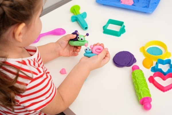 Top 18 ideias de presentes criativos para um Dia das Crianças inesquecível 2 Mãos de criança moldando caracóis com massinha colorida, em uma atividade criativa e lúdica que estimula a imaginação e a coordenação motora.