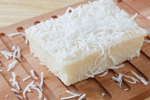 Pedaço de bolo de tapioca cortado e servido sobre uma superfície de madeira.