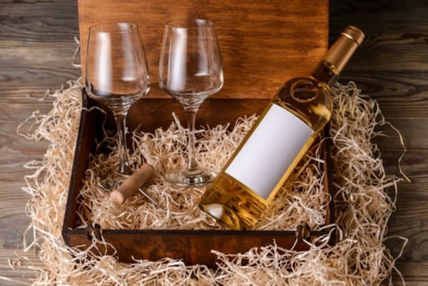 12 ideias de presentes de Natal para homens que nunca falham 3 Caixa com garrafa de vinho e duas taças sobre uma mesa de madeira, em ambiente elegante e acolhedor.