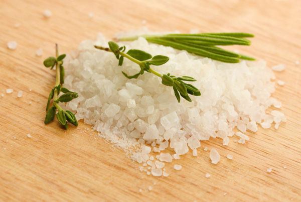 Como limpar energia da casa? Técnicas de limpeza para renovar seu lar 3 Sal grosso com alecrim fresco e ramos de tomilho sobre superfície de madeira rústica.