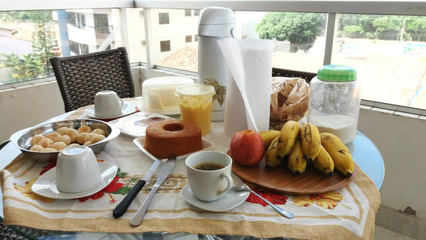 Mesa de café da manhã com pratos, xícara de café e alimentos variados, criando um cenário convidativo e bem organizado. 