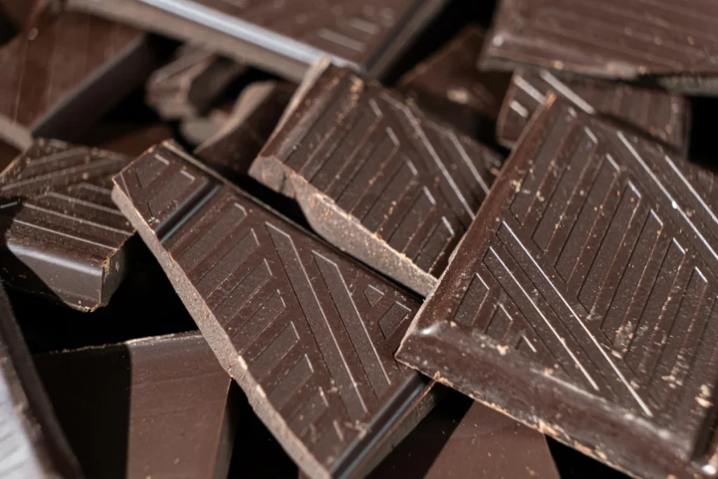 Pedaços de chocolate meio amargo com padrões geométricos em relevo empilhados.