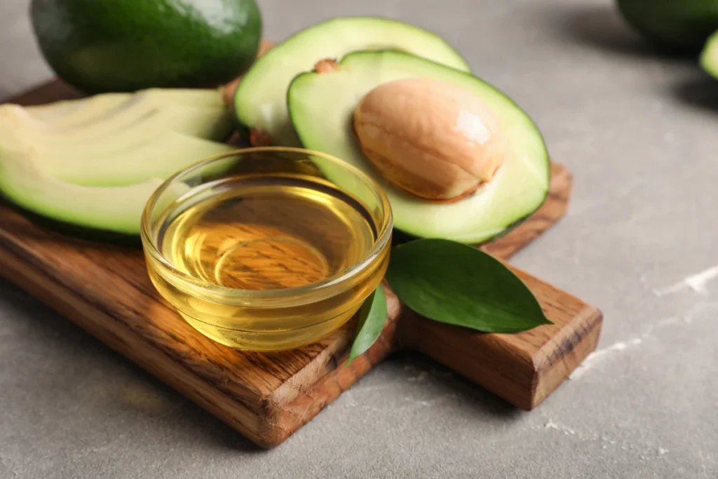  Tigela de óleo de abacate dourado acompanhada de fatias de abacate fresco.