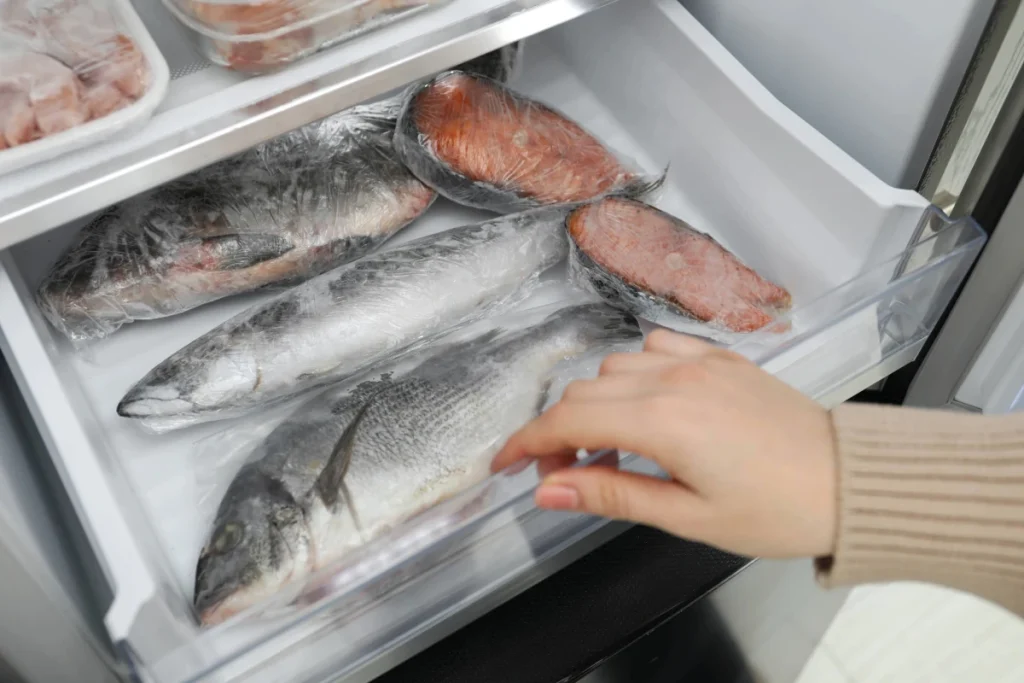 Peixes inteiros e postas de peixes congelados, armazenados dentro de freezer da geladeira.