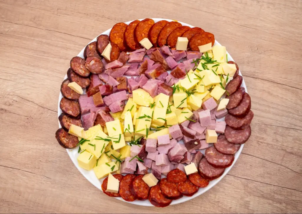 O que servir no almoço de Páscoa: 3 sugestões de cardápios completos para a família 4 Aperitivo de frios organizado de forma circular. As fatias de salame e linguiça rodeiam cubos de queijo e presunto, servindo como uma opção prática para ser servido antes do almoço de Páscoa.