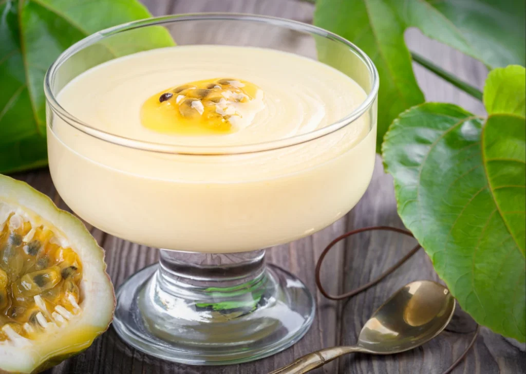 Uma taça de vidro com mousse de maracujá cremoso decorado com polpa e sementes da fruta.