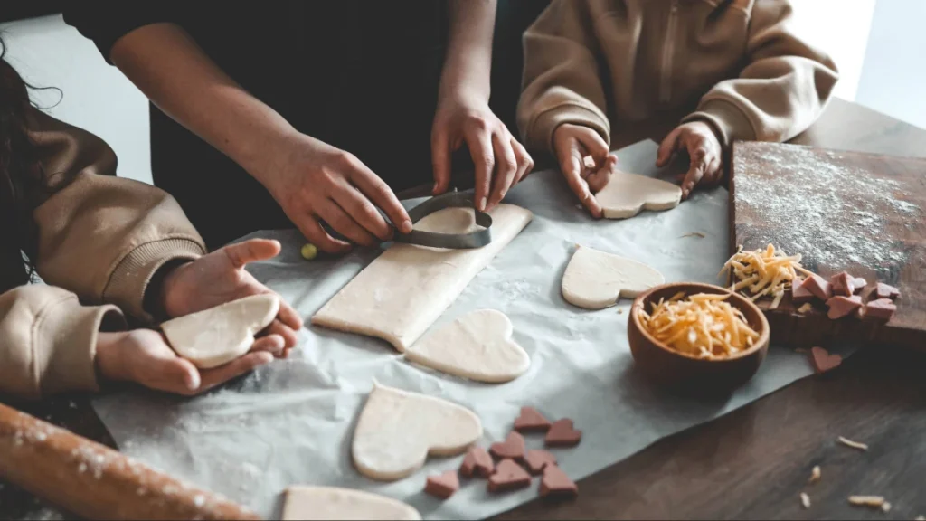 O que dar de presente no Dia das Mães? 24 ideias para todos os bolsos 2 Pai e filhos preparando biscoitos artesanais em formato de coração para o Dia das Mães.