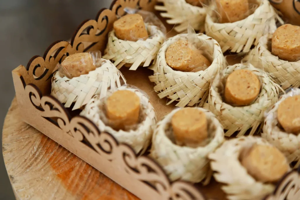 Paçoca caseira embalada dentro de chapeuzinho de palha em cima de bandeja de madeira