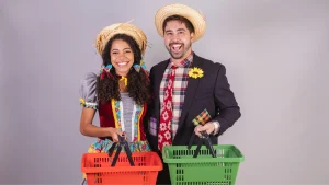 Casal com traje típico da festa junina com cesta de compras na mão.
